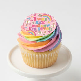 I Was Six Now I'm Seven edible topper on rainbow buttercream cupcake